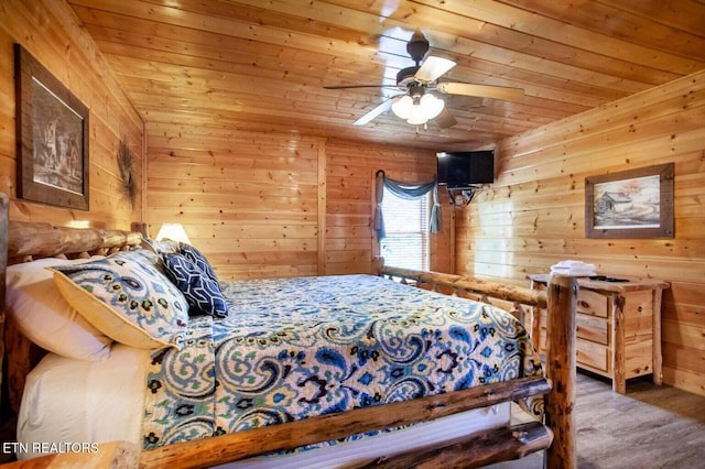 bedroom with wooden walls, wood ceiling, ceiling fan, and wood finished floors