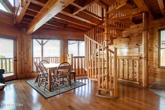 unfurnished dining area with wood walls, stairs, a healthy amount of sunlight, and hardwood / wood-style floors