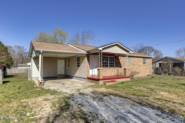 view of front facade with fence, a carport, a front lawn, dirt driveway, and brick siding