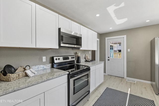 kitchen with light stone counters, light wood-style flooring, recessed lighting, appliances with stainless steel finishes, and white cabinetry