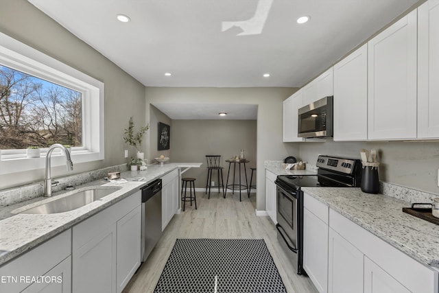 kitchen featuring light stone counters, recessed lighting, a sink, stainless steel appliances, and white cabinets