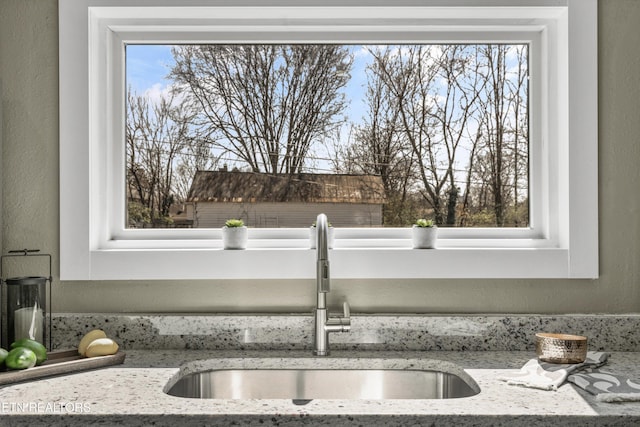 details with a sink, light stone countertops, and a textured wall