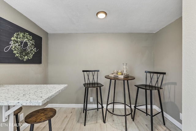 dining room with wood finished floors, baseboards, and a textured ceiling