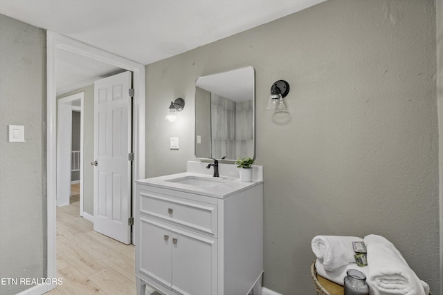 bathroom featuring wood finished floors, vanity, and a textured wall