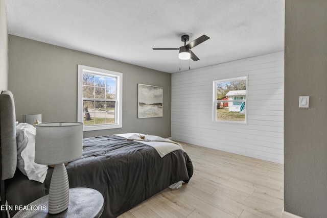 bedroom featuring light wood-type flooring, a textured ceiling, and ceiling fan