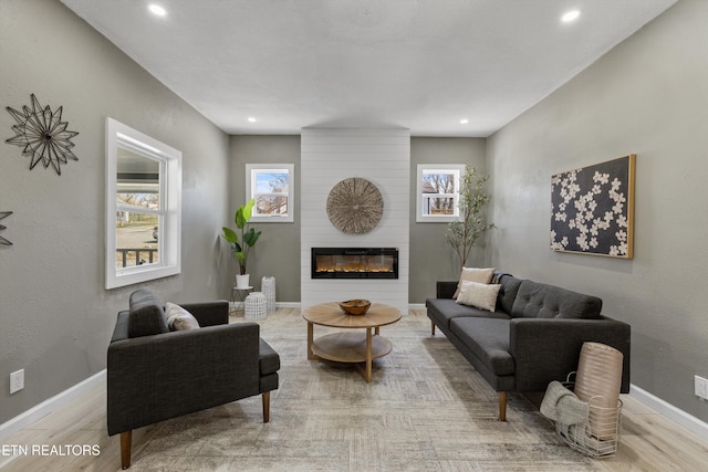 living room featuring recessed lighting, wood finished floors, baseboards, and a large fireplace