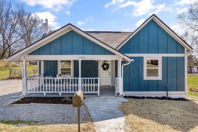 view of front of home featuring board and batten siding, covered porch, roof with shingles, and a chimney