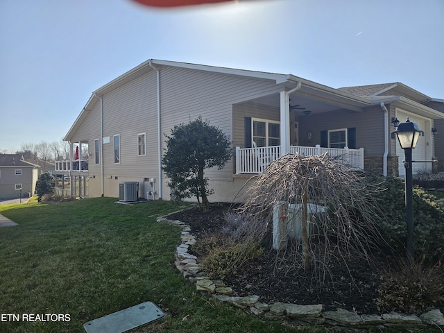 view of home's exterior featuring central air condition unit, a lawn, and covered porch