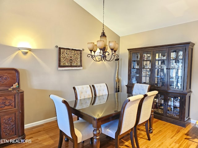 dining room featuring baseboards, lofted ceiling, an inviting chandelier, and light wood finished floors