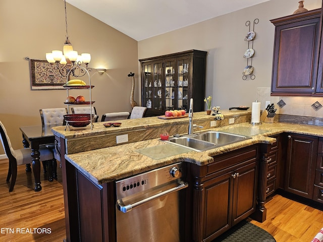 kitchen featuring vaulted ceiling, a peninsula, light wood-type flooring, and a sink