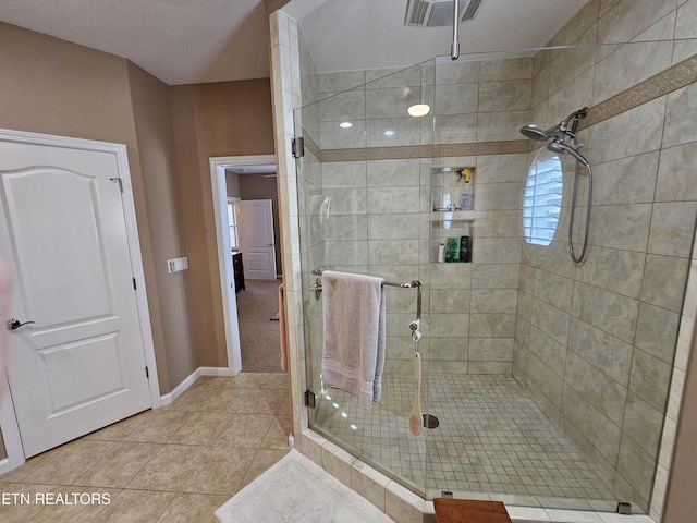 bathroom with tile patterned flooring, visible vents, a stall shower, and baseboards