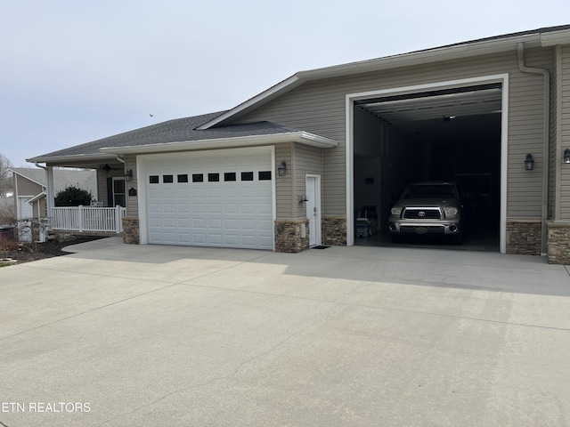 exterior space with stone siding, concrete driveway, and a garage