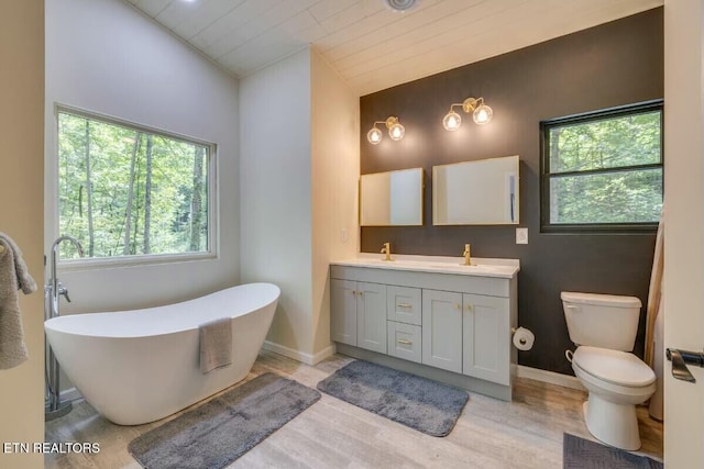 bathroom with double vanity, a freestanding tub, toilet, and a sink