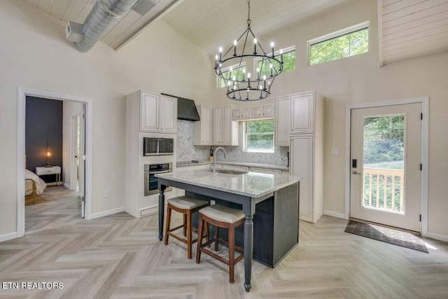 kitchen featuring oven, high vaulted ceiling, light stone counters, a sink, and tasteful backsplash