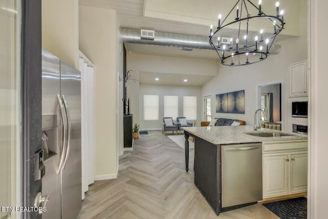 kitchen featuring light stone countertops, a sink, stainless steel appliances, a towering ceiling, and open floor plan