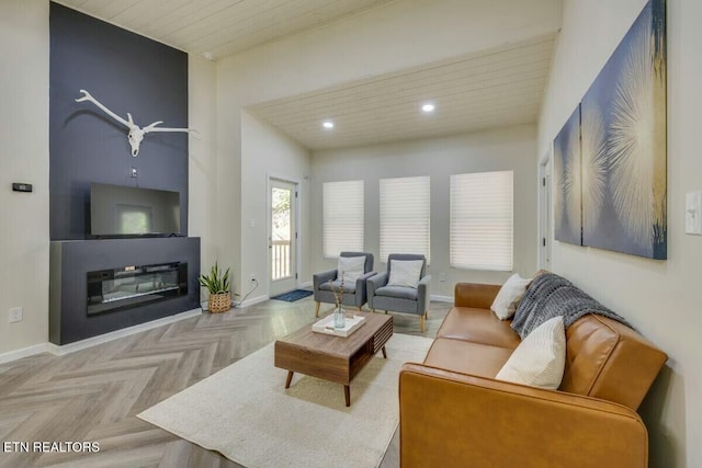 living area featuring a glass covered fireplace, recessed lighting, and baseboards