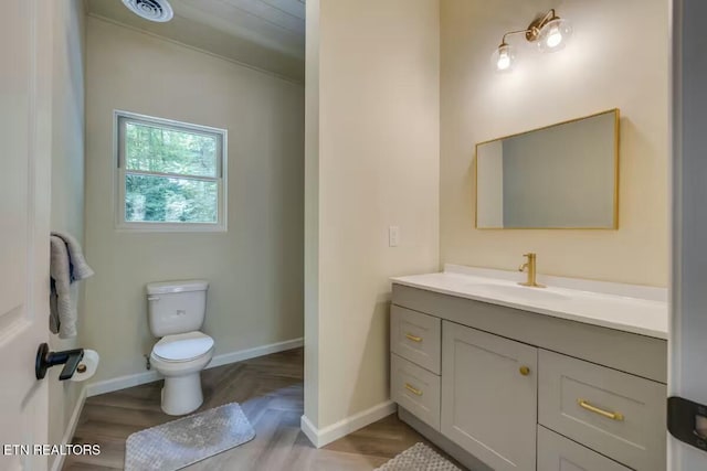 bathroom with visible vents, baseboards, toilet, wood finished floors, and vanity