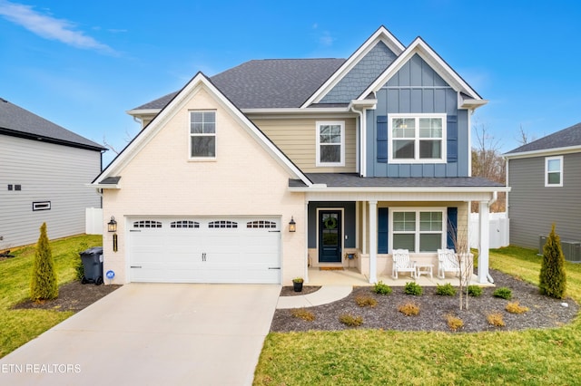 view of front facade with driveway, a front lawn, a porch, board and batten siding, and an attached garage