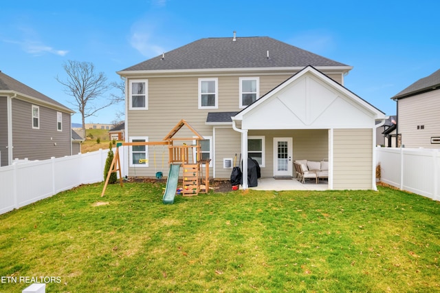 rear view of property featuring a yard, a playground, a fenced backyard, and a patio area