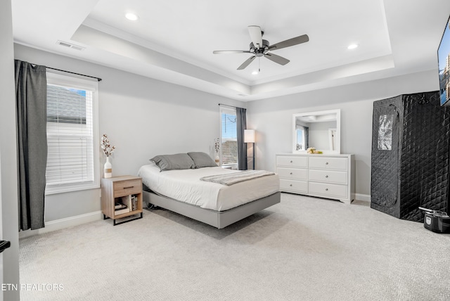 bedroom featuring light carpet, visible vents, a raised ceiling, and baseboards