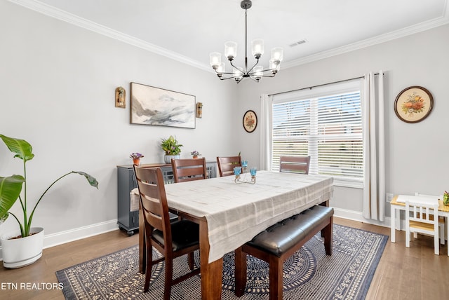 dining area with visible vents, wood finished floors, baseboards, and ornamental molding