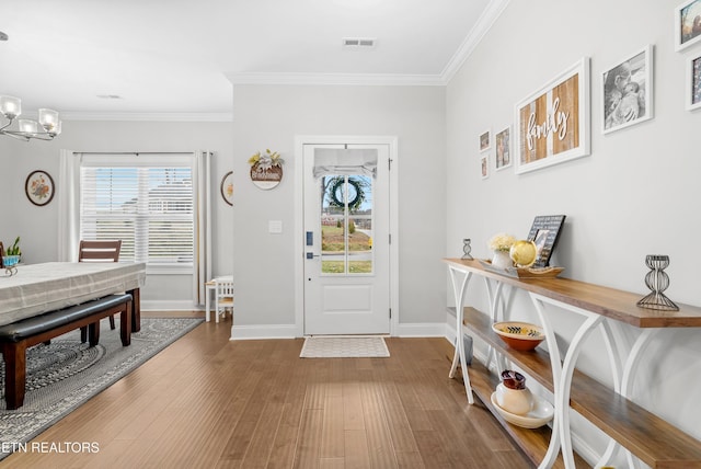 foyer featuring wood finished floors, visible vents, a chandelier, and ornamental molding