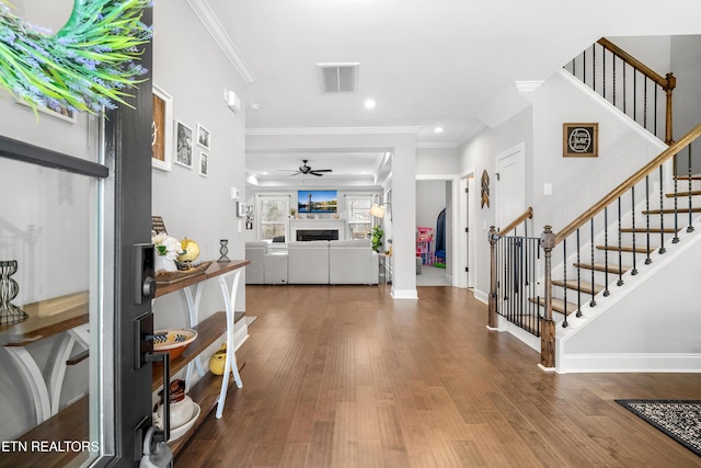 entryway with visible vents, a fireplace, stairs, and wood finished floors