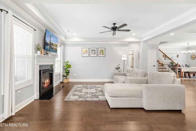 living area featuring visible vents, wood finished floors, a glass covered fireplace, and ornamental molding