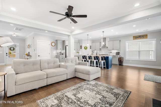 living area featuring visible vents, crown molding, baseboards, and dark wood-style flooring