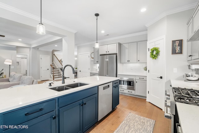 kitchen featuring light wood-style flooring, stainless steel appliances, a sink, light countertops, and open floor plan