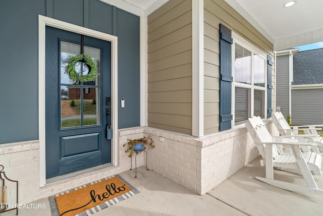 property entrance with a porch and brick siding