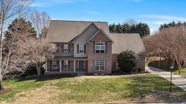 view of front of property featuring brick siding, covered porch, concrete driveway, and a front lawn