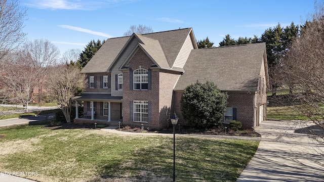 view of front of home with a front yard, driveway, covered porch, a garage, and brick siding