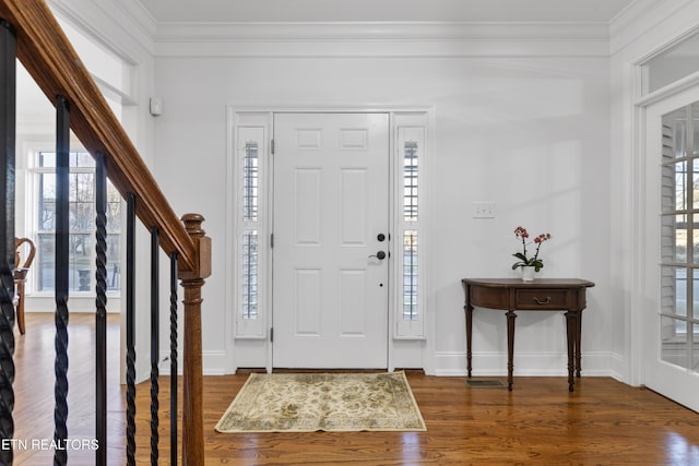 entrance foyer featuring crown molding, stairway, wood finished floors, and baseboards