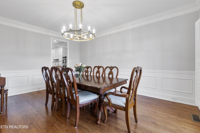 dining space with visible vents, a wainscoted wall, a notable chandelier, crown molding, and dark wood-style flooring