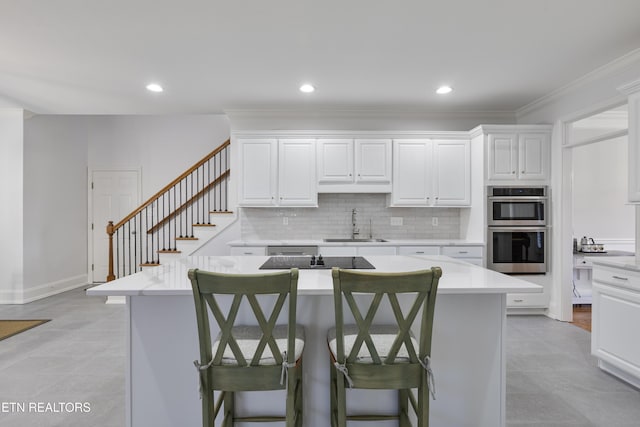 kitchen featuring a sink, light countertops, black electric cooktop, and stainless steel double oven