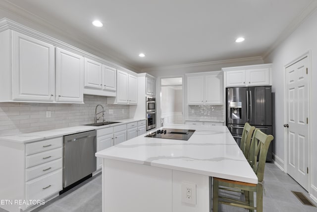 kitchen featuring ornamental molding, a sink, a center island, white cabinetry, and appliances with stainless steel finishes