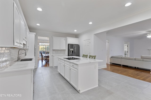 kitchen with crown molding, white cabinets, stainless steel refrigerator with ice dispenser, and a center island