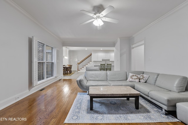 living room with visible vents, wood finished floors, a ceiling fan, and ornamental molding