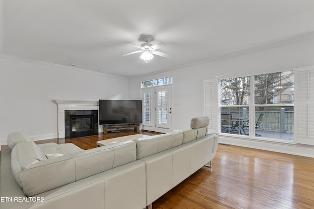 living room featuring ornamental molding, a tile fireplace, ceiling fan, and wood finished floors