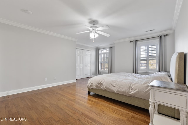 bedroom featuring visible vents, crown molding, and wood finished floors