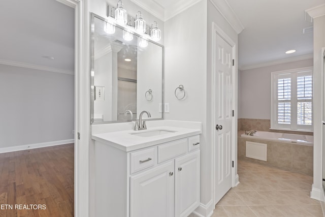 full bath with tile patterned floors, vanity, a garden tub, and ornamental molding