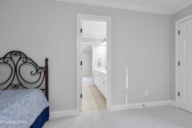 bedroom with baseboards, ensuite bath, a sink, light carpet, and crown molding