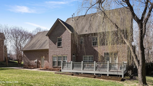 rear view of property with brick siding, a deck, and a yard