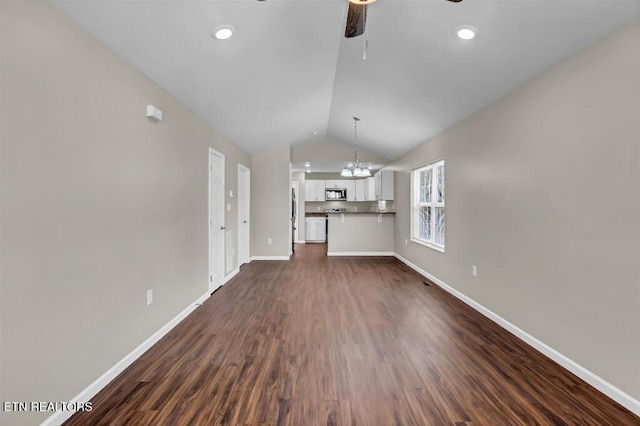 unfurnished living room with baseboards, vaulted ceiling, recessed lighting, ceiling fan with notable chandelier, and dark wood-style floors