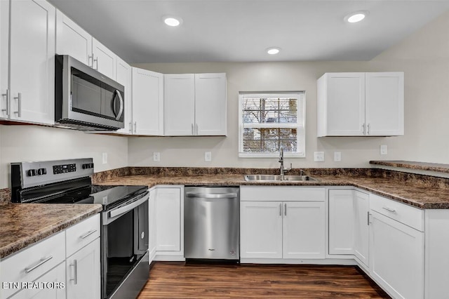 kitchen with dark countertops, white cabinets, appliances with stainless steel finishes, and a sink