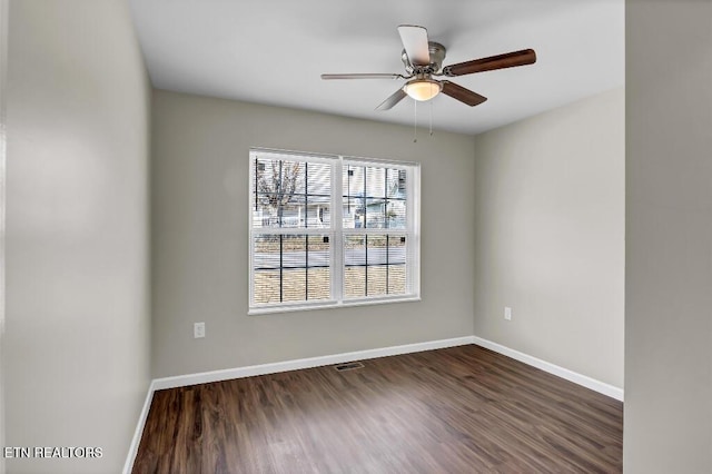 empty room with wood finished floors, visible vents, and baseboards