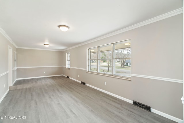 empty room featuring visible vents, baseboards, wood finished floors, and crown molding