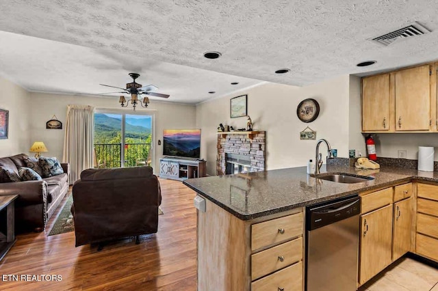 kitchen with visible vents, a sink, stainless steel dishwasher, open floor plan, and a peninsula