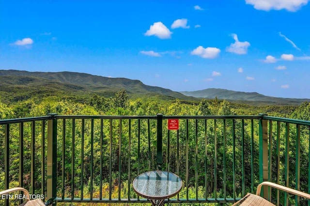 balcony featuring a mountain view and a view of trees